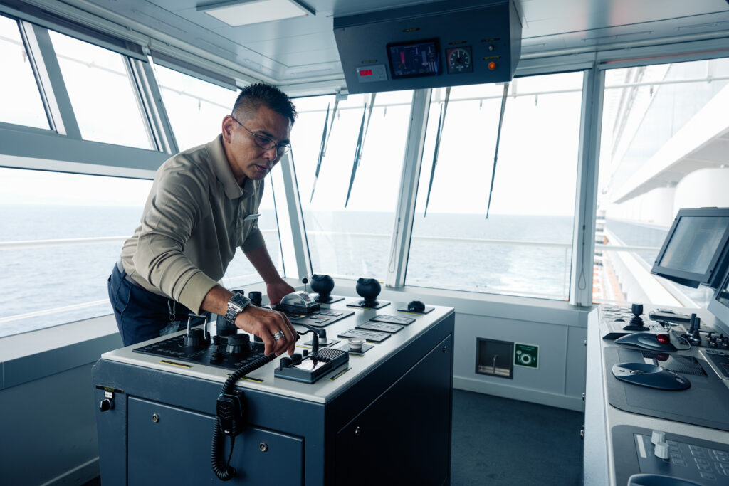 Cruise ship officer adjusting controls on the ship's bridge.
