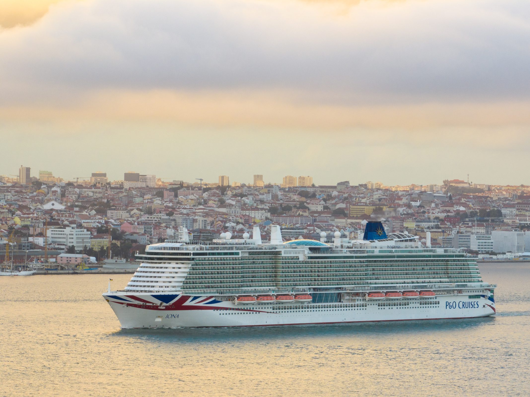 Cruise ship sailing with a city in the background.