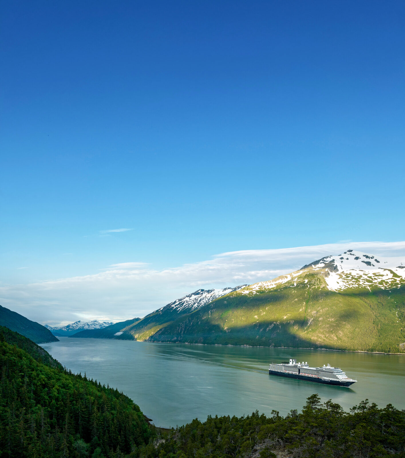 Nieuw Amsterdam sailing near Skagway, surrounded by majestic mountains.